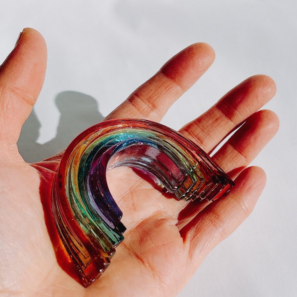 手のひらに乗ったガラスアート「虹のオブジェ」。手作りの温もりが伝わる。