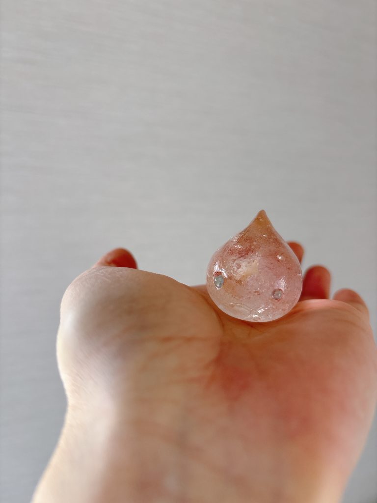 ガラスのダンゴウオ。透明感のあるピンク系の色合いで、気泡が内部に浮かんでいる。