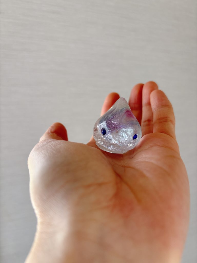 正面に近い角度から見たガラスのダンゴウオ。青い目が左右に離れ、柔らかいガラスの質感が際立つ。