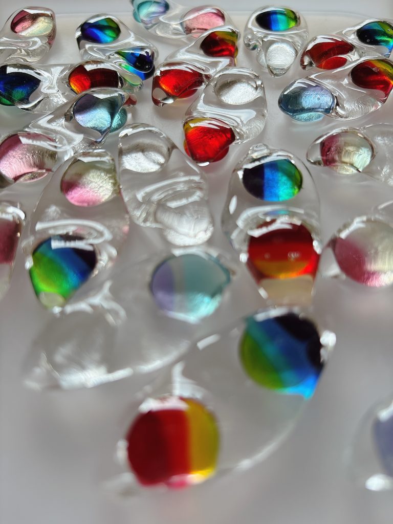 枝豆をモチーフにした透明感のある箸置きが並んでいる。
赤・青・緑などのカラフルな模様があしらわれ、光にきらめいて見える。