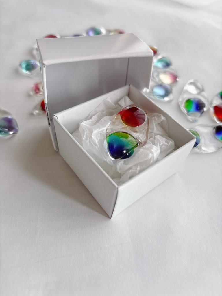 白い箱の中に緩衝材とともに収められた枝豆箸置き。カラフルなガラスの豆が二粒並び、手元に届く姿が丁寧に表現されている。