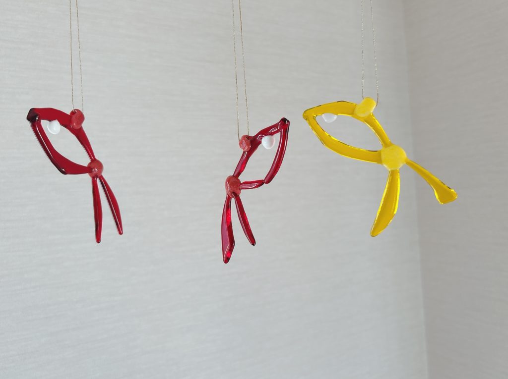 赤と黄色のフレーム状ガラスで作られた3匹の魚のオブジェ。透明感と軽やかさのあるデザイン。
