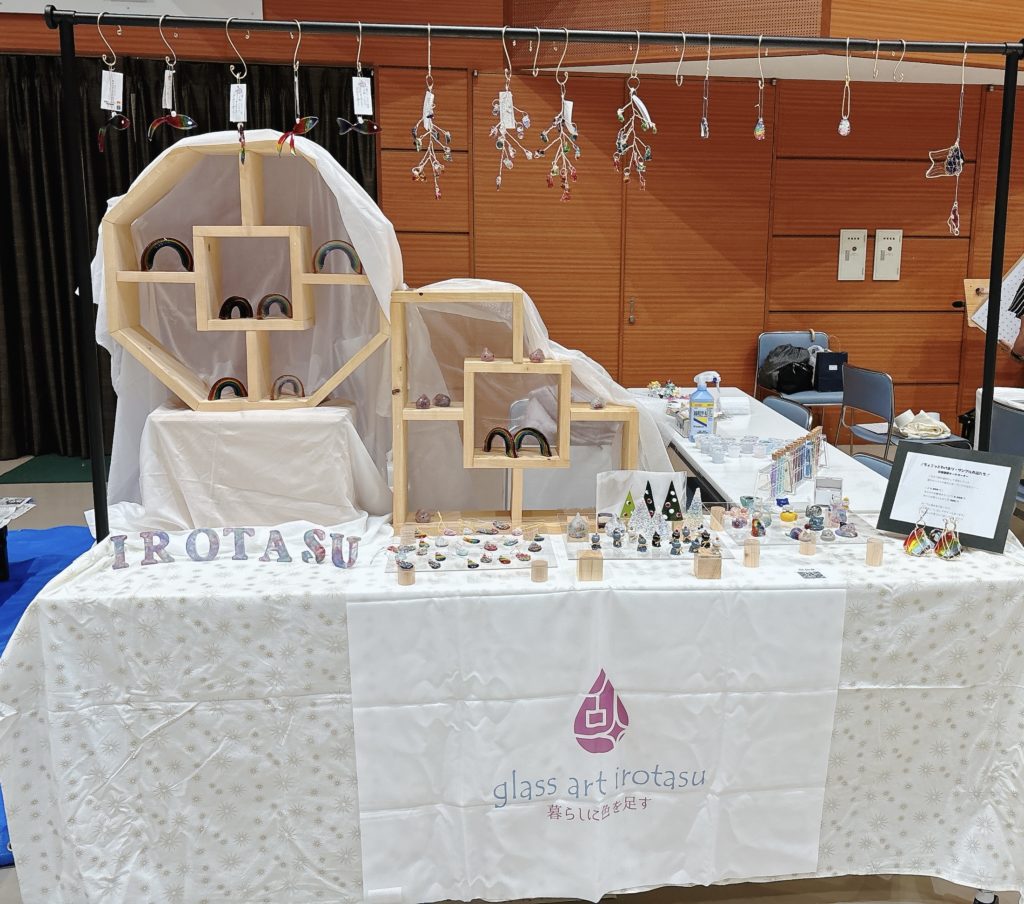かててマルシェのブース全景。虹色のガラス作品やモビールがディスプレイされたglass art irotasuの出店風景。